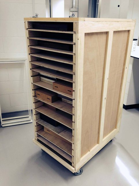 A wooden trolley with several rows to move museum collections.